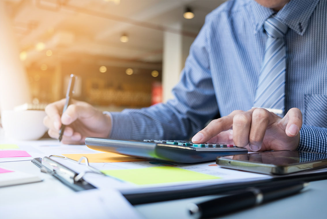 Close-up of business accountant using calculator while working i