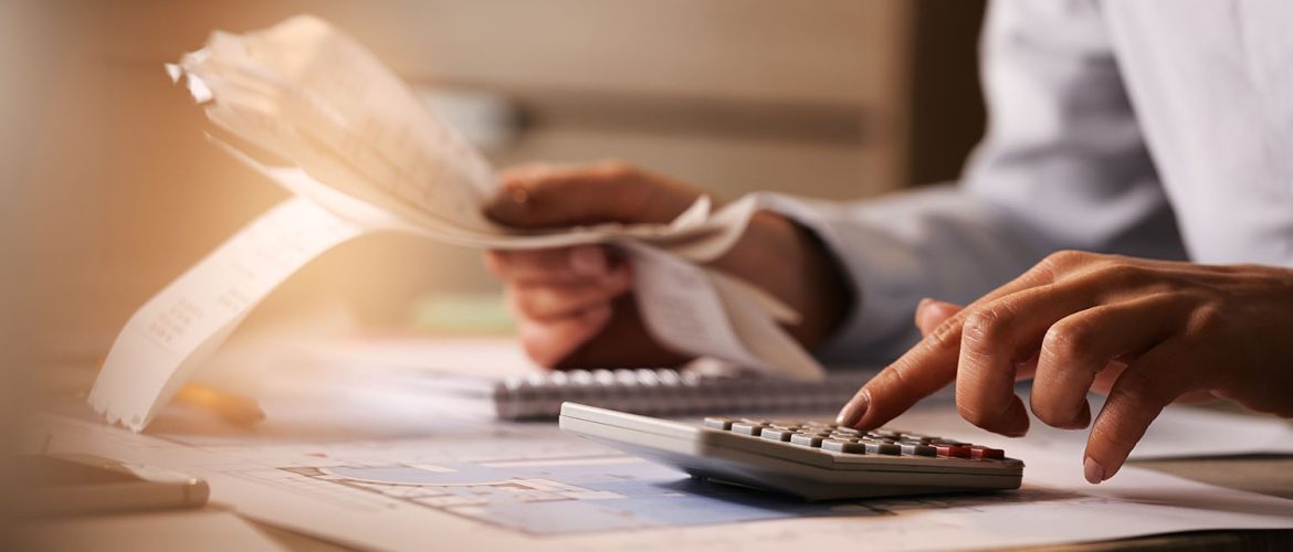 Close-up of business accountant using calculator while working i Close-up of economist using calculator while going through bills and taxes in the office.